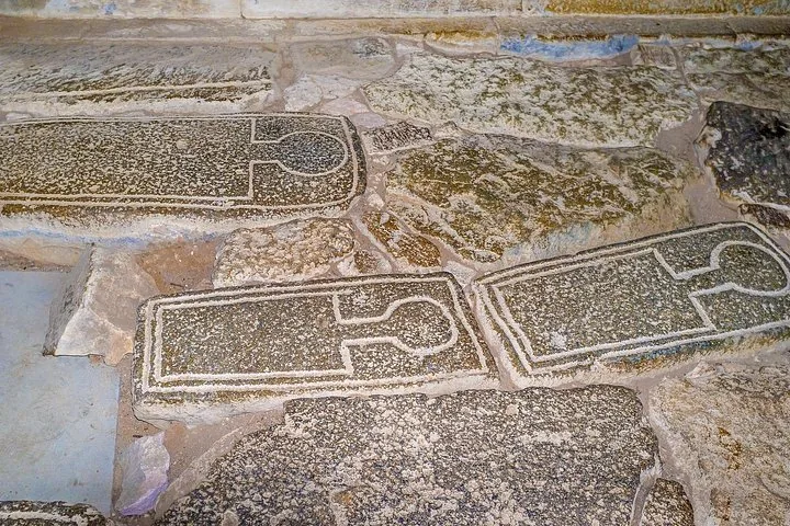 Ancient stone carvings and inscriptions on the floor of a historic site.