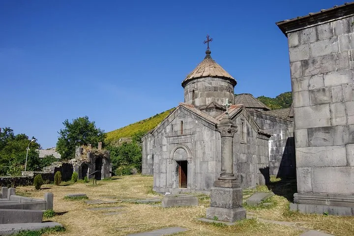 Exterior view of a stone church and ruins at Haghpat Monastery complex.
